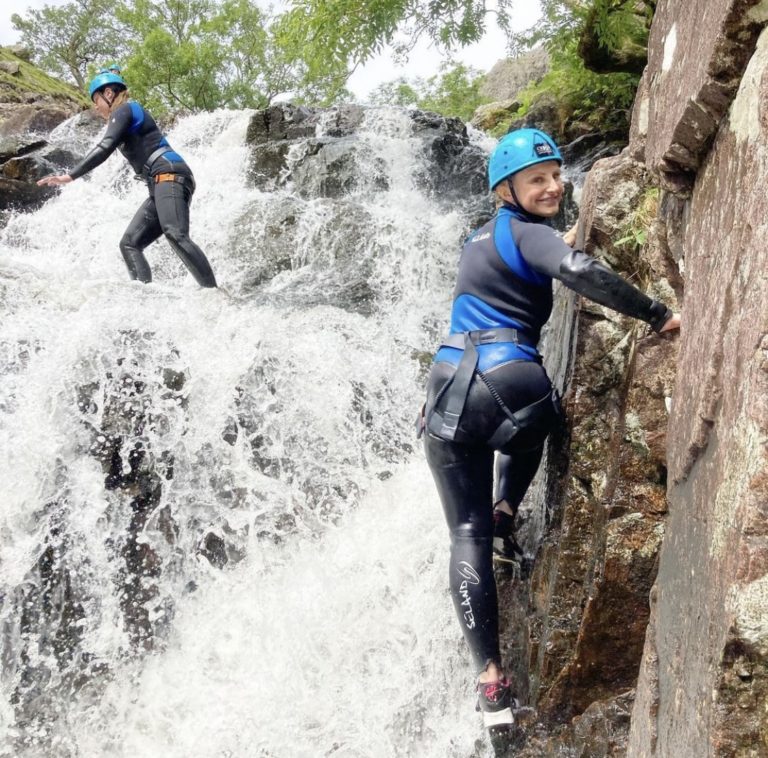woman climbing a waterfall at Langdale in the Lake District during a ghyll scramble