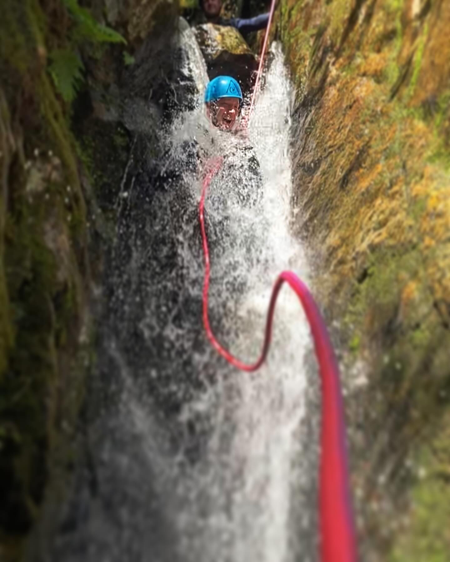 Man in a waterfall whilst abseiling during a canyoning trip in the Lake District