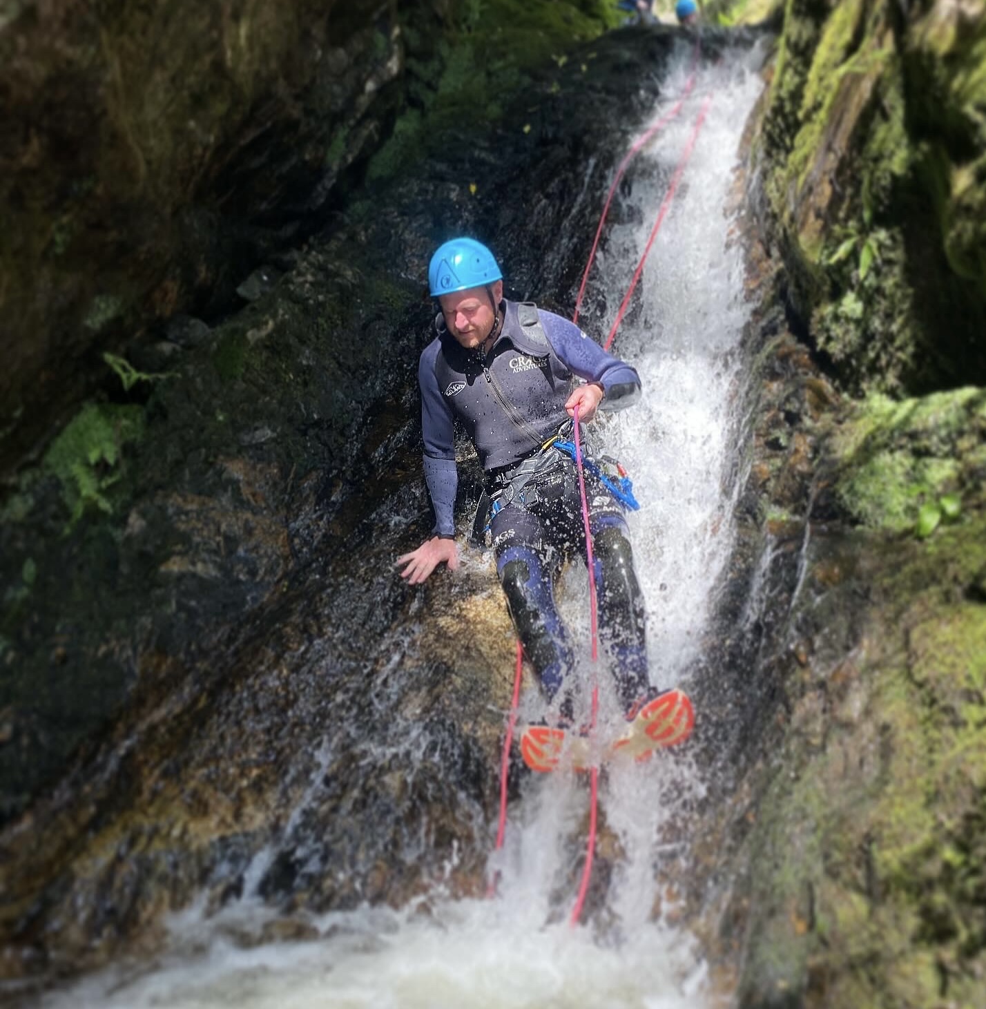 Canyoning man coming down a waterfall