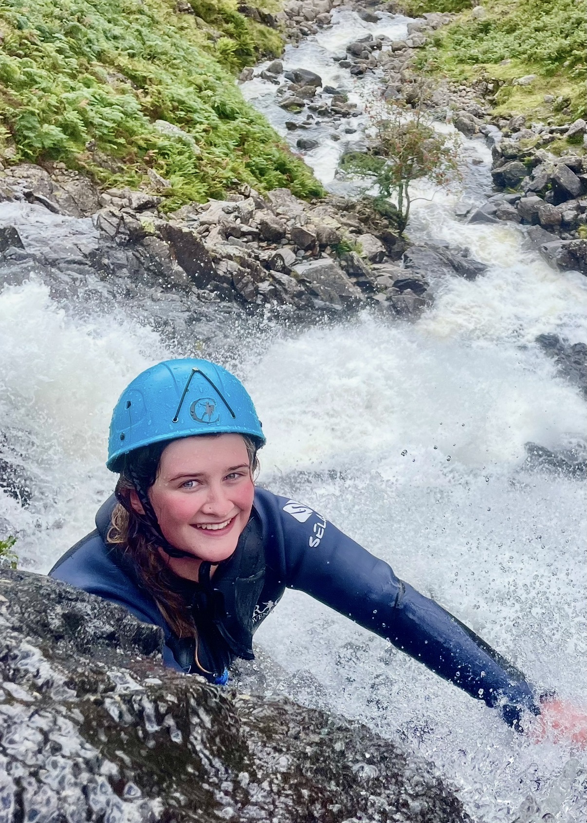 a woman climbing up a mountain stream in the lake district