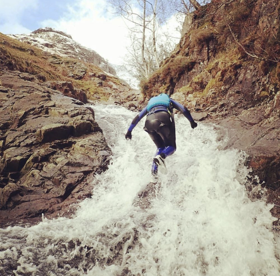 a man ascending a mountain ghyll in the Lake District as part of an organised ghyll scramble