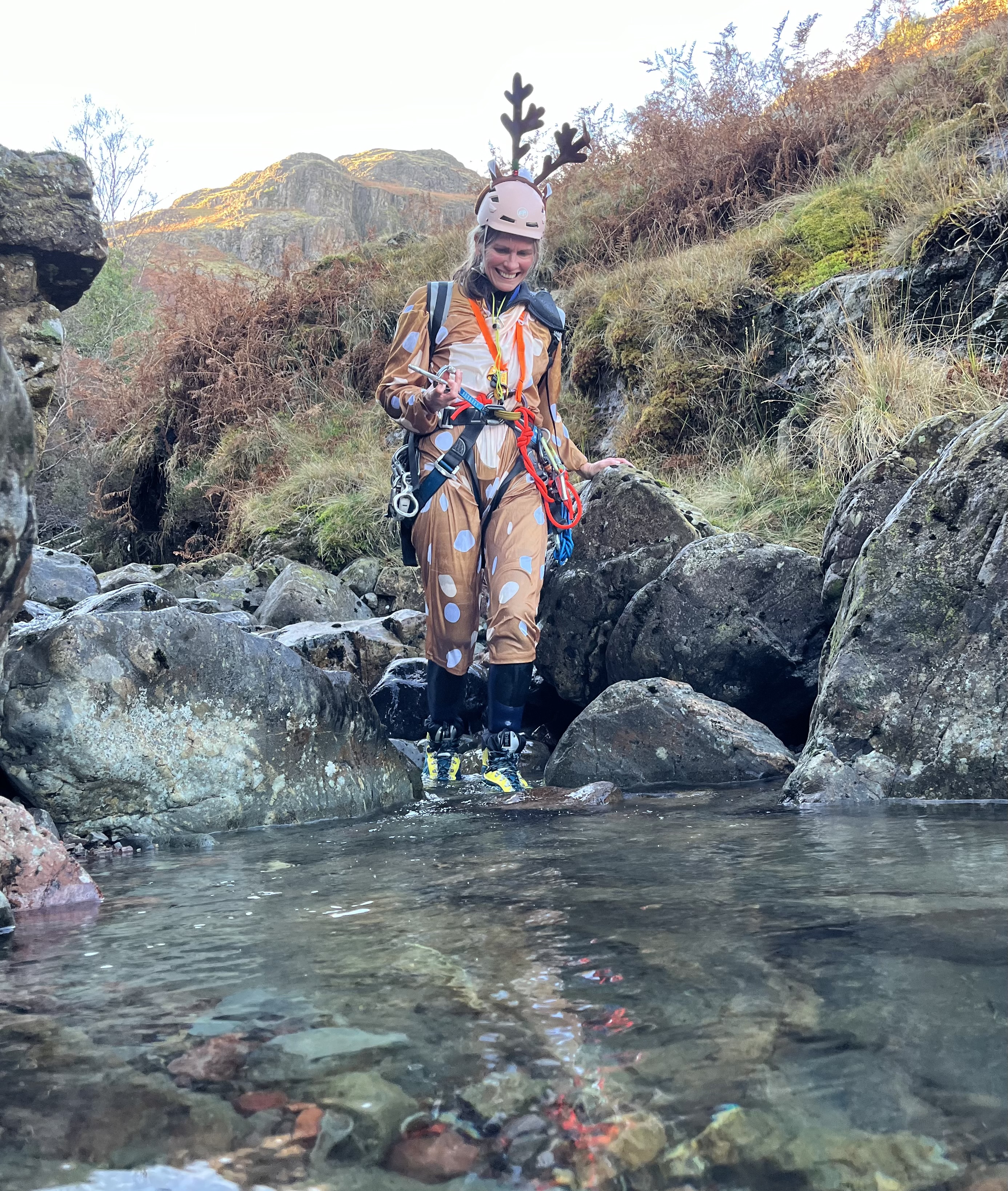 a woman dressed as a reindeer walking in a mountain stream called a canyon in the Lake District