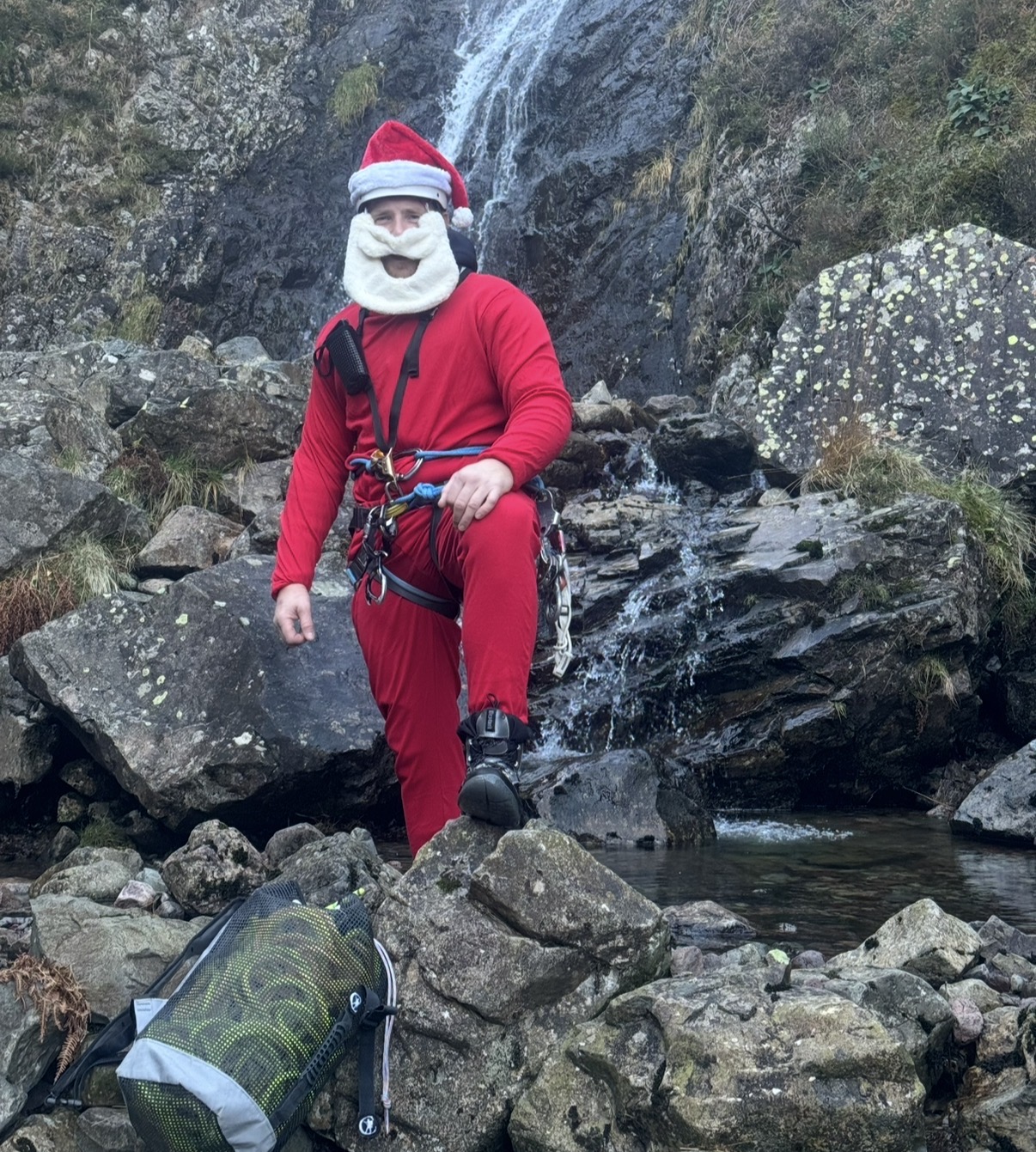a man in a Santa suit walking in a mountain stream