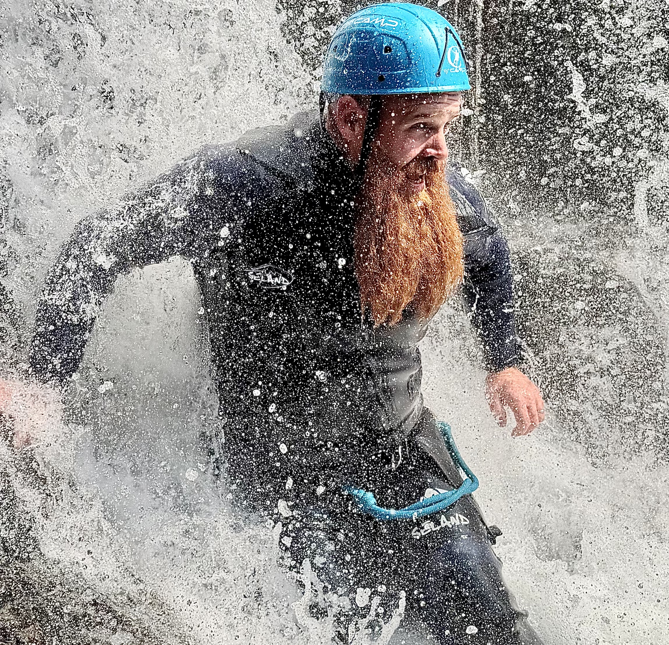 a man with a long ginger bread in a waterfall, during a ghyll scramble in the Lake District