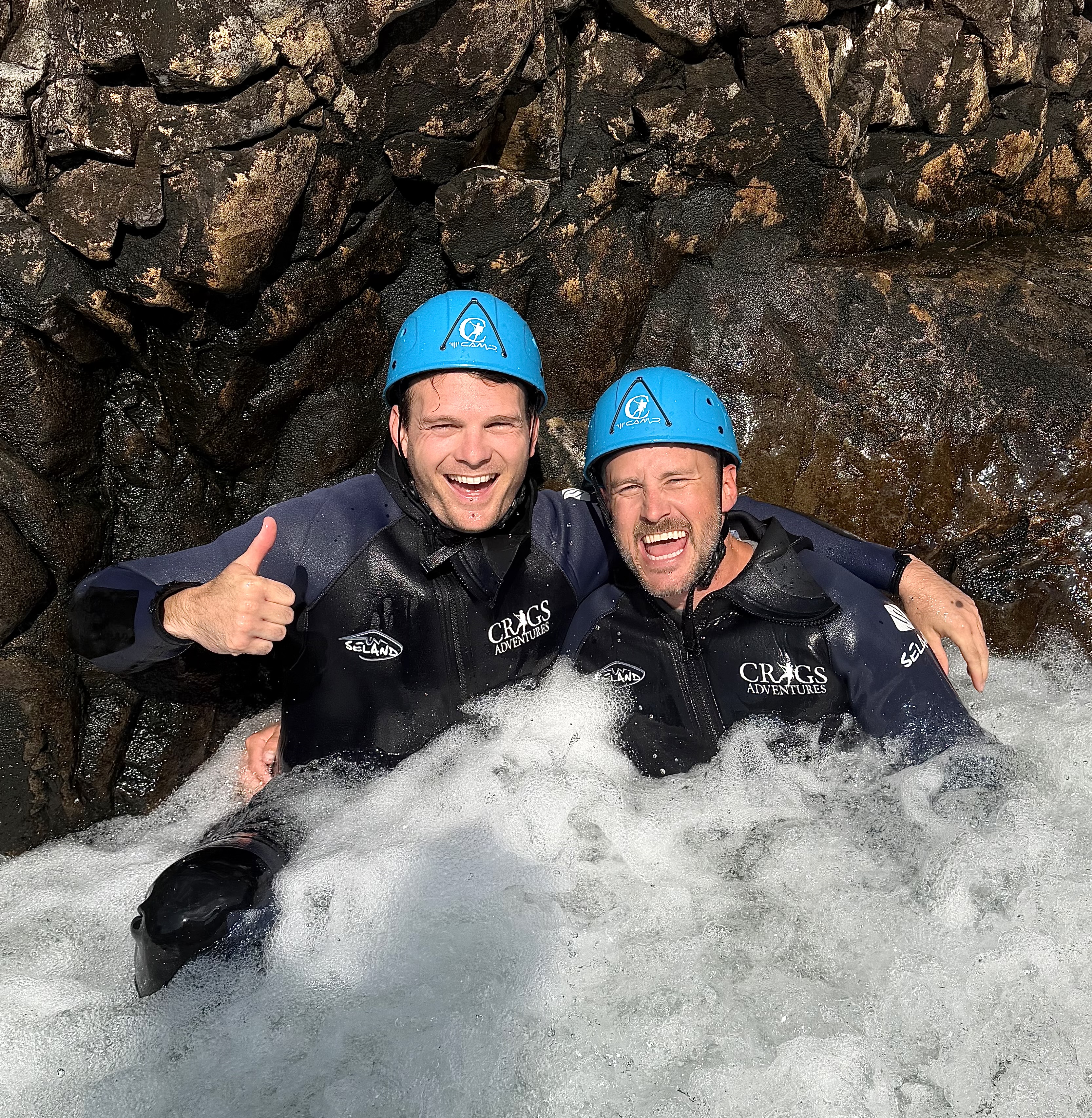 two men with their arms around each other laughing in a pool of water, at Esk Ghyll
