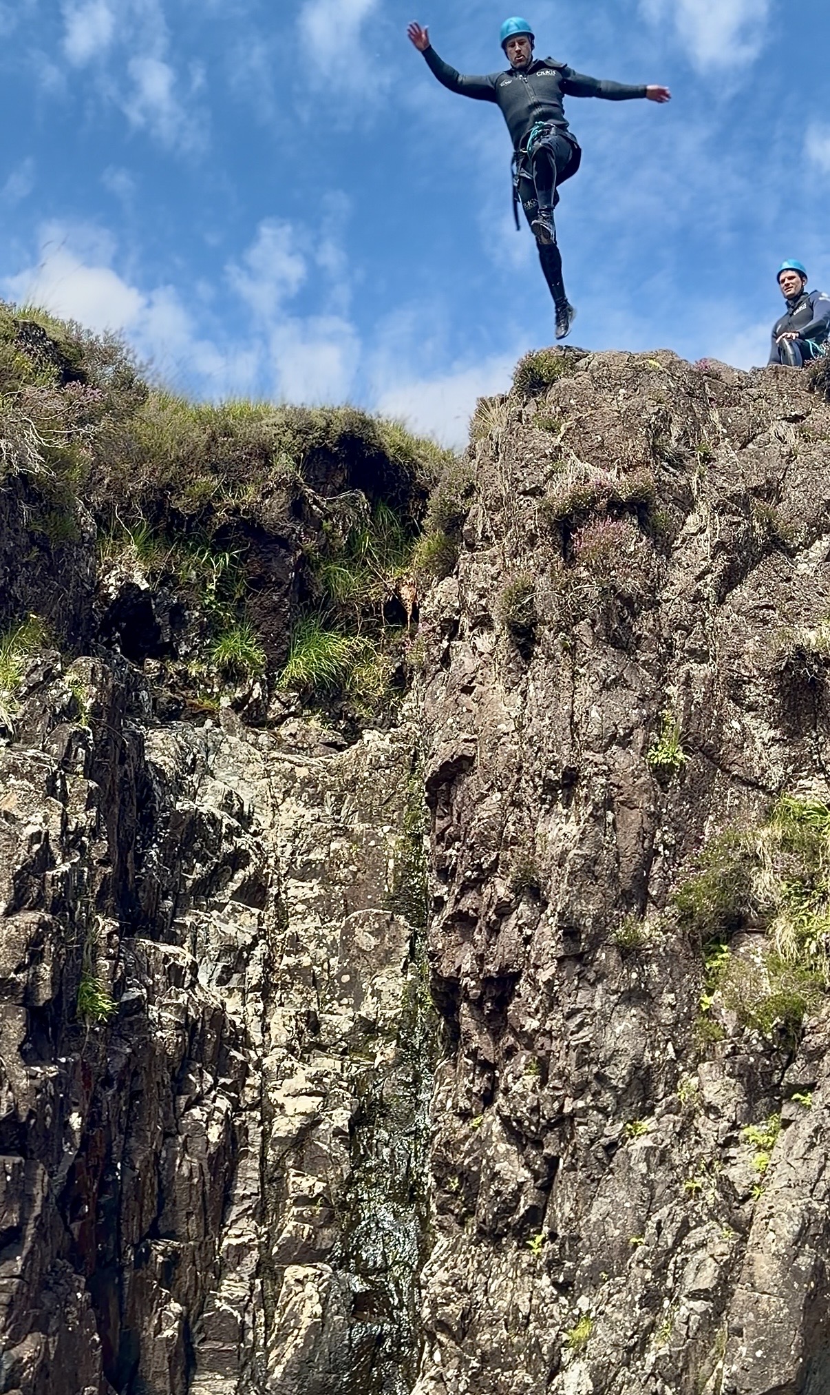 a man leaping off a high cliff into a pool of water