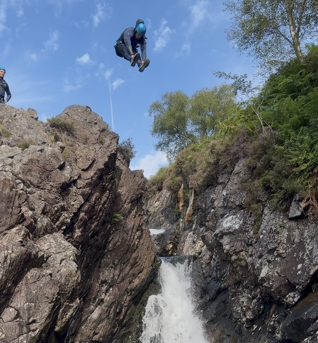 a man jumping off a rocky cliff assuming the pike position